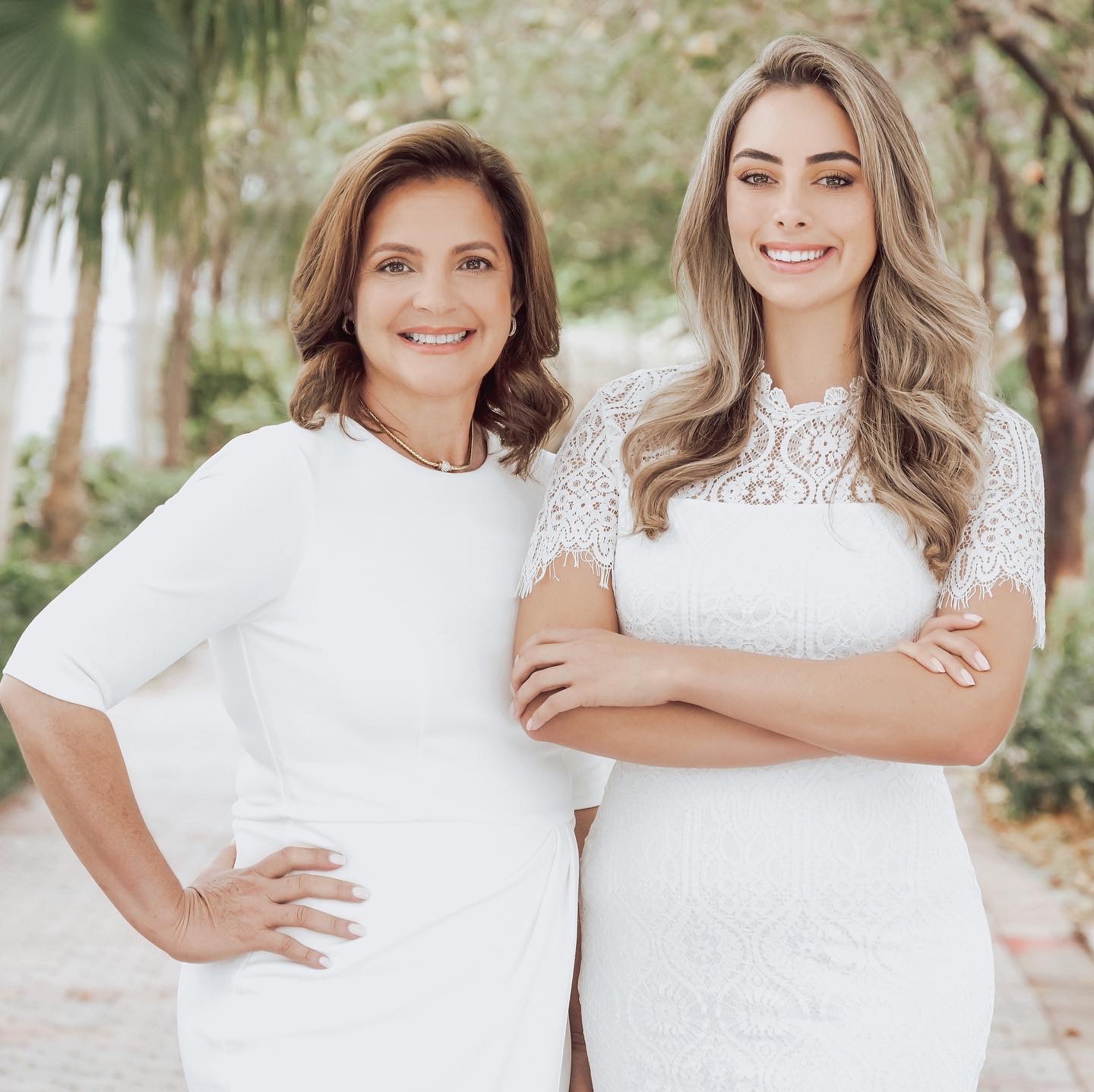 A warm headshot of a mother and daughter, both smiling confidently, standing side by side. The image highlights their close bond as a mother-daughter team working together in real estate.